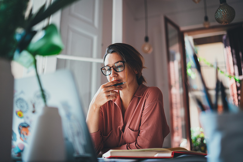 businesswoman thinking while sitting front open laptop