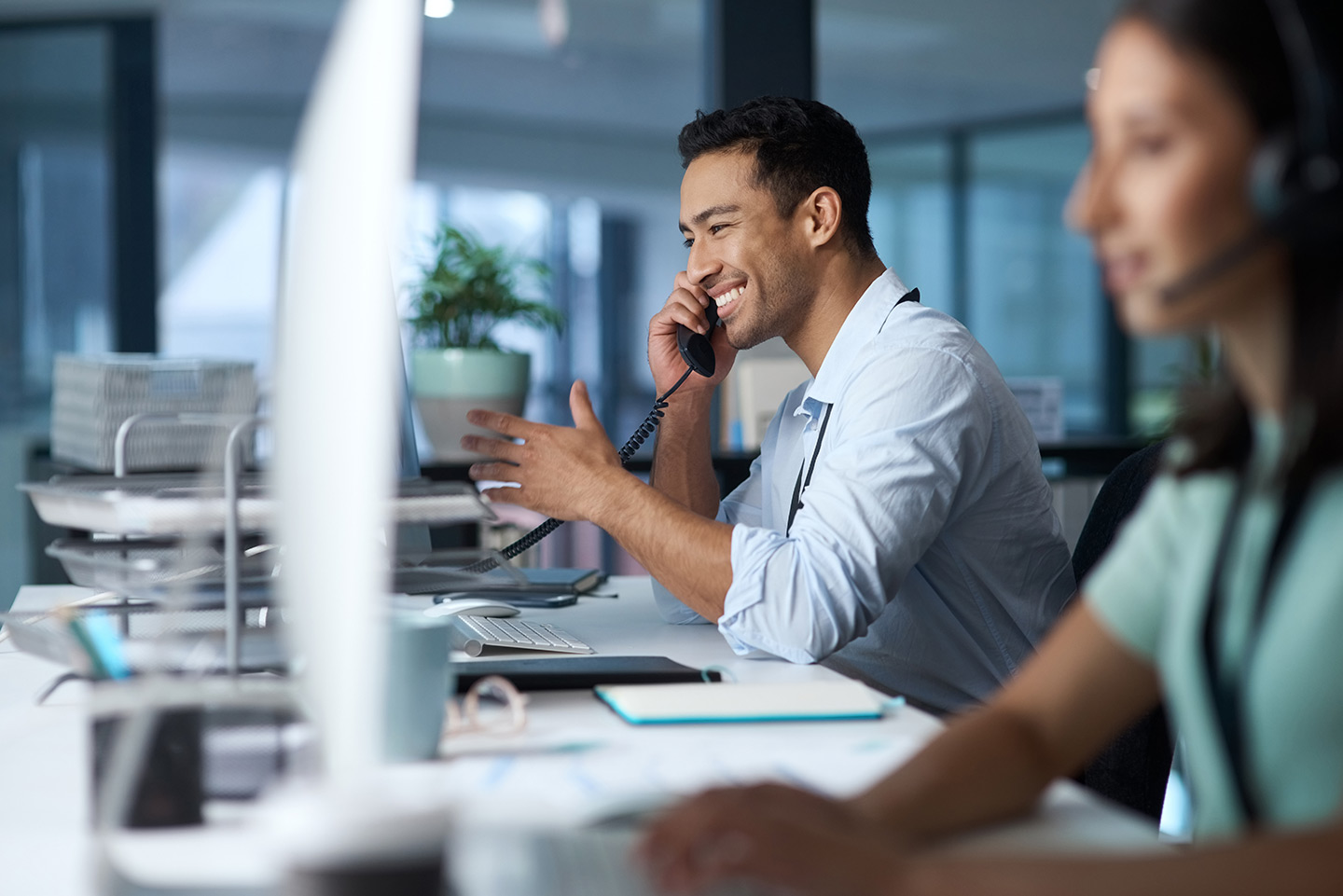young man answering the phone while working in a modern call centre.